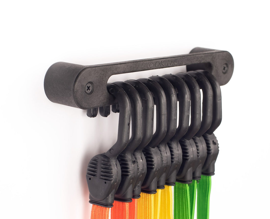 Flat bungee cords in orange, yellow, and green hanging on an AV1 Hook Rail